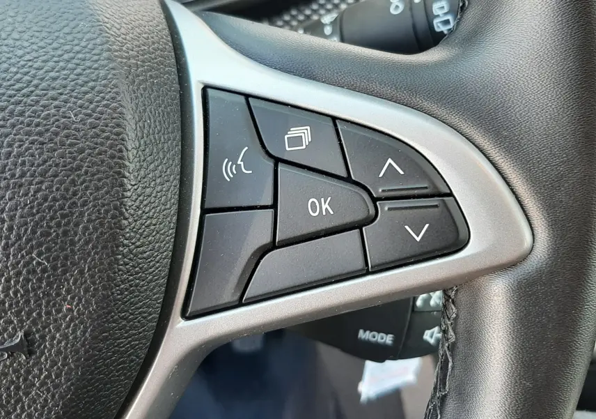 Gros plan sur les commandes multifonctions à droite du volant en cuir noir du Dacia Sandero Stepway gris schiste 2025.