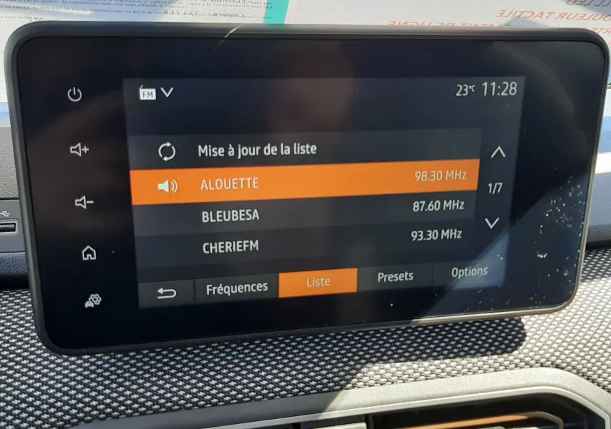 Écran tactile central de la Dacia Sandero Stepway 2025 affichant la liste des stations radio, avec tableau de bord gris texturé.
