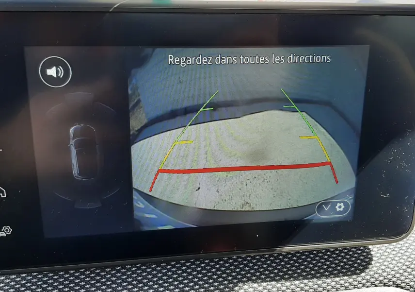 Écran multimédia montrant la caméra de recul d'une Dacia Sandero Stepway gris schiste, avec lignes de guidage colorées.