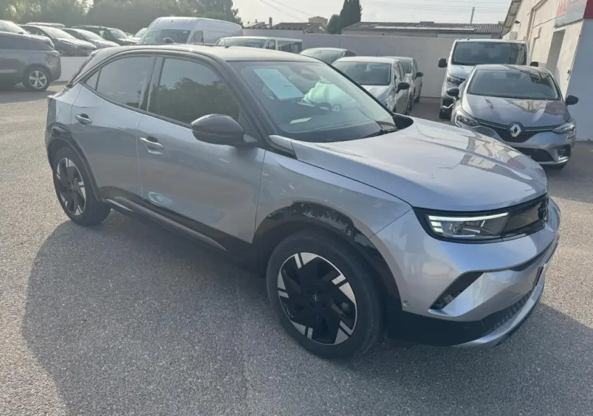 Opel Mokka électrique gris en 3/4 avant droit, avec jantes alliage noires et vitres surteintées.