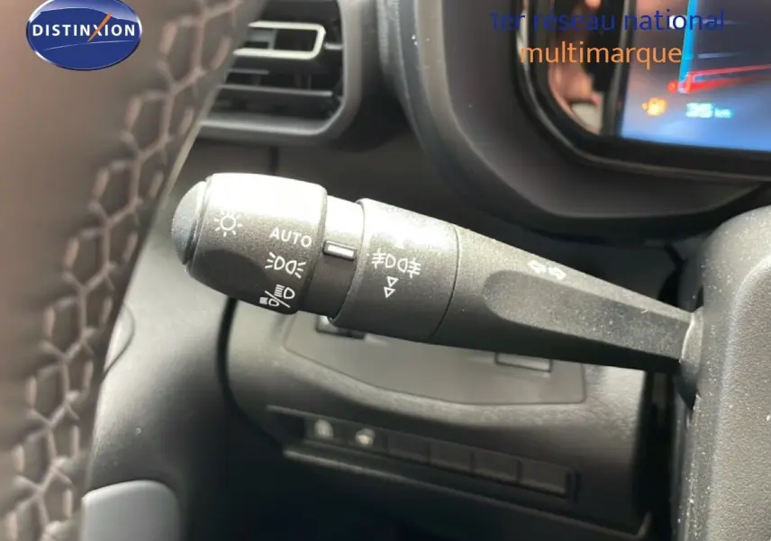 Gros plan sur la commande des feux à gauche du volant dans l’habitacle noir du Citroën Berlingo gris 2026.