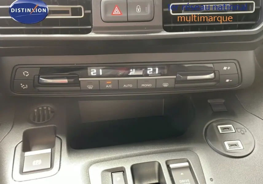 Vue rapprochée du tableau de bord et console centrale du Citroën Berlingo gris, montrant la climatisation digitale et ports USB.