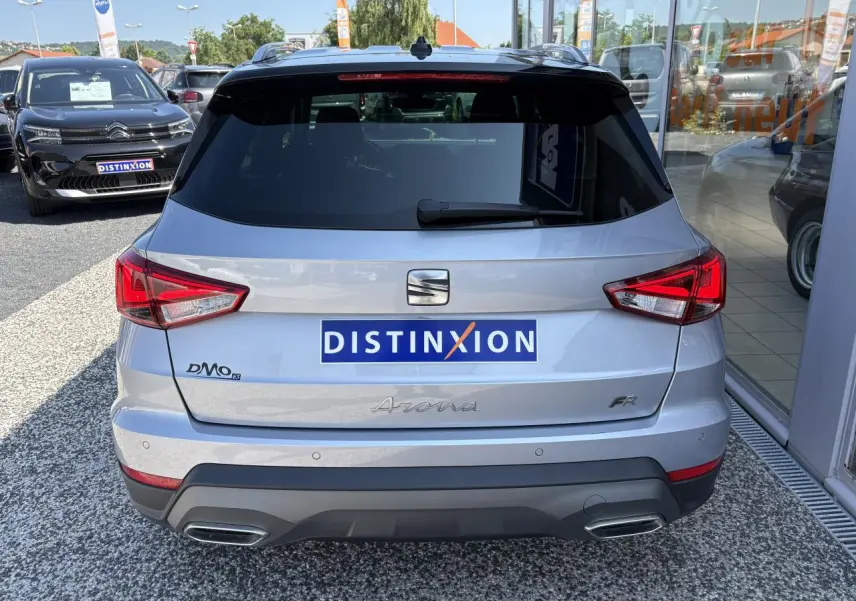 Vue arrière d'un SEAT Arona 2024 gris clair avec logos distinctifs et double sortie d'échappement intégrée.