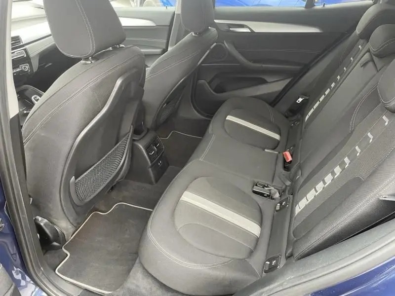 Vue intérieure côté arrière droit du BMW X2 bleu métal 2021, montrant les sièges arrière en tissu noir avec bandes grises.
