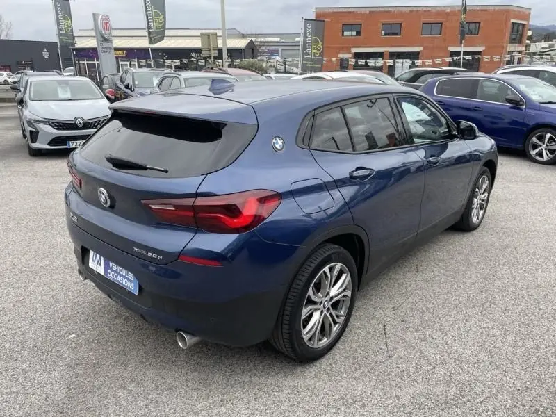 Vue 3/4 arrière droite d’un BMW X2 bleu métal 2021, version X-Drive 20 da Lounge avec jantes alliage et vitres teintées.