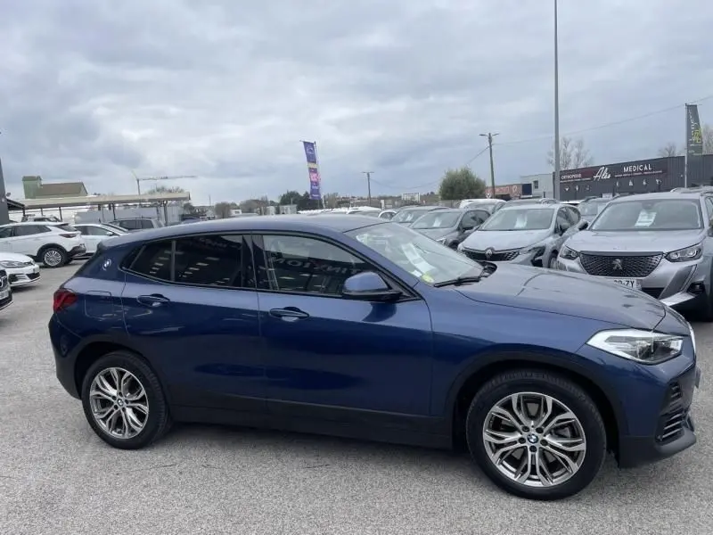 BMW X2 X-Drive 20 da 2021 bleu métal vue de profil côté gauche, avec jantes alliage et vitres teintées.