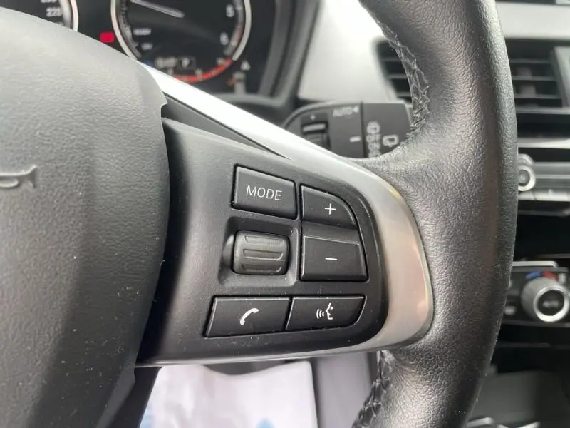 Gros plan sur les commandes au volant côté gauche du BMW X2 bleu métal 2021, version X-Drive 20 da Lounge.
