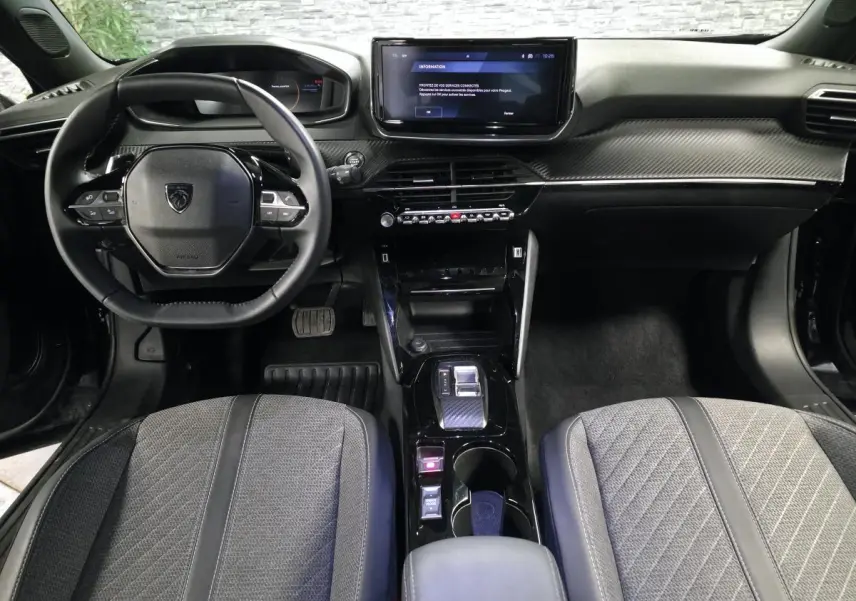 Vue intérieure avant du Peugeot 2008 2025 noir, avec tableau de bord carbone et écran tactile central.