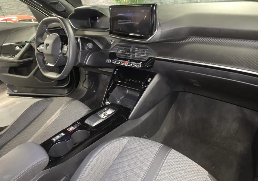 Vue intérieure côté conducteur du Peugeot 2008 noir 2025, mettant en valeur le tableau de bord et la console centrale moderne.