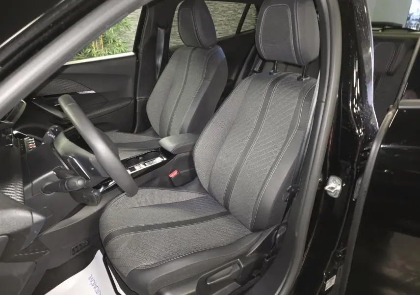 Vue intérieure côté conducteur de la Peugeot 2008 noire, mettant en valeur les sièges tissu et cuir avec surpiqûres Quartz.