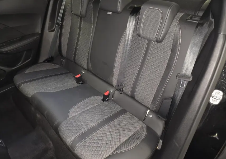 Vue intérieure de la banquette arrière noire et grise du Peugeot 2008 1.2i Hybrid 2025 avec ceintures et appuie-têtes.