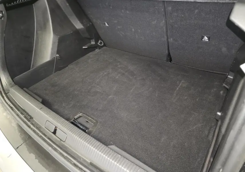 Vue intérieure du coffre noir du Peugeot 2008 1.2i Hybrid 2025, montrant la surface de chargement et les sièges arrière rabattus.