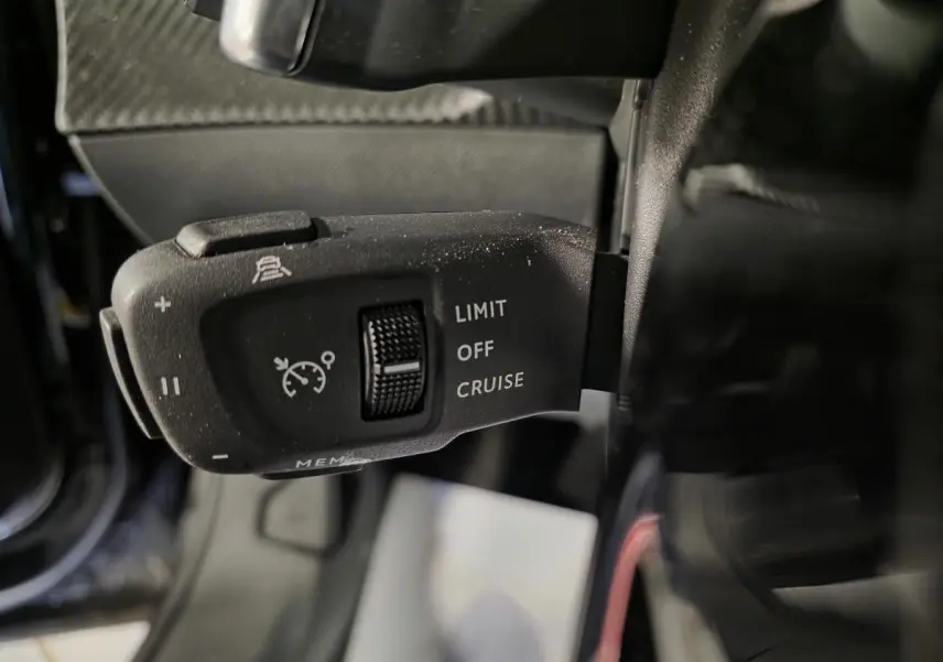 Gros plan sur la commande de régulateur de vitesse du Peugeot 2008 noir, côté gauche du volant.