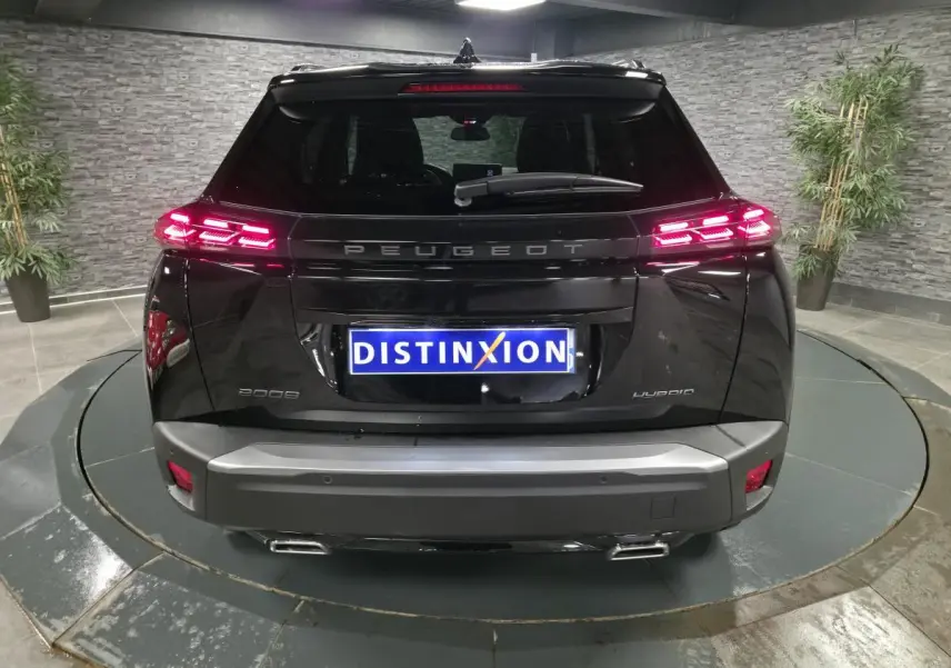 Vue arrière d'un Peugeot 2008 noir avec feux arrière LED allumés et double sortie d'échappement chromée.