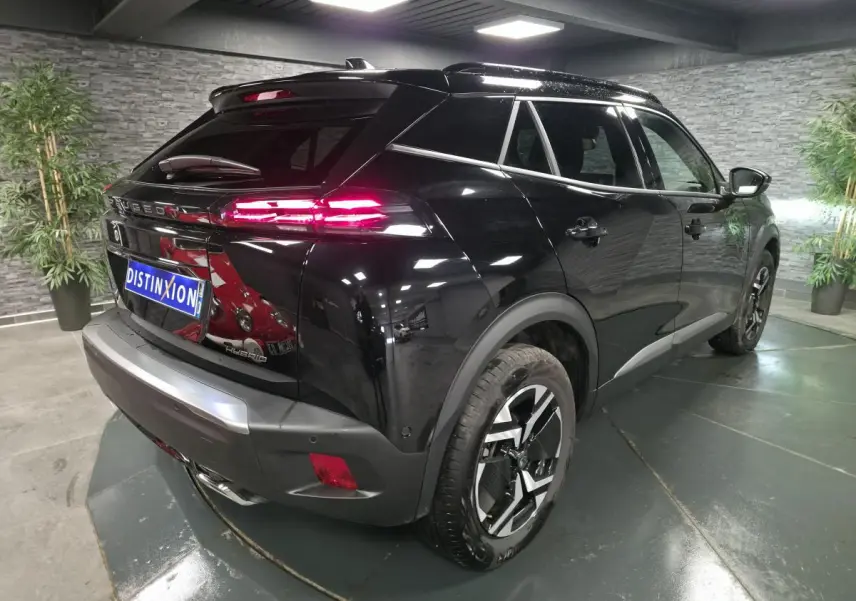 Vue 3/4 arrière droite du Peugeot 2008 noir avec feux arrière LED allumés et jantes alliage bi-ton.