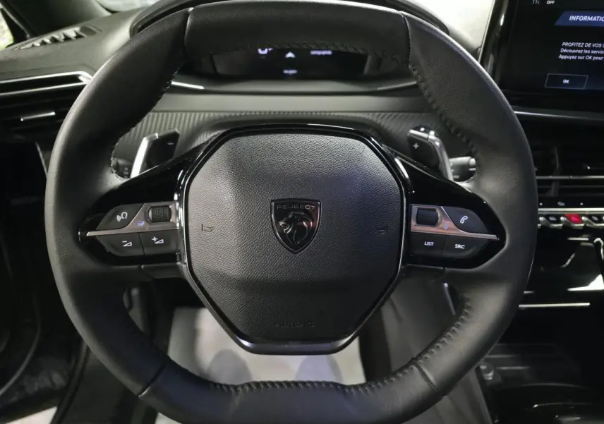 Vue rapprochée du volant compact en cuir noir avec commandes multimédia intégrées du Peugeot 2008 1.2i Hybrid 2025.