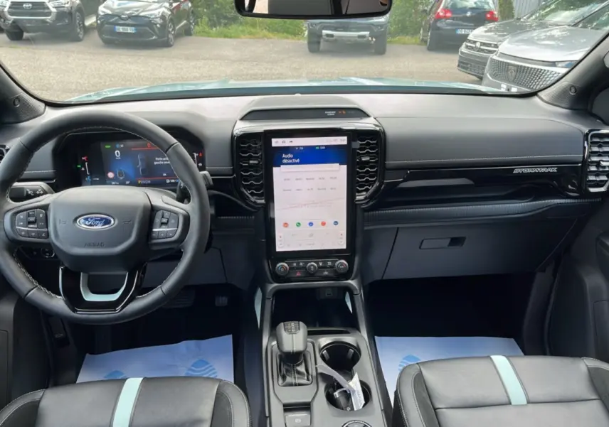 Vue intérieure avant du Ford Ranger gris zen 2026, tableau de bord avec écran tactile vertical et volant multifonctions cuir.