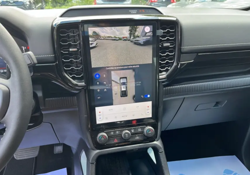 Vue intérieure centrée sur l’écran tactile vertical du Ford Ranger gris zen avec commandes climatisation et volant partiel visible.