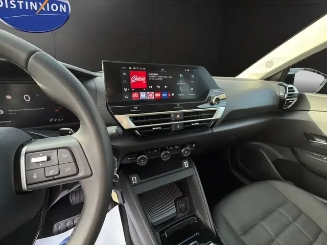 Intérieur du Citroën C4 Hybride 2025 vu côté conducteur, tableau de bord avec écran tactile 10 pouces et volant cuir multifonctions.