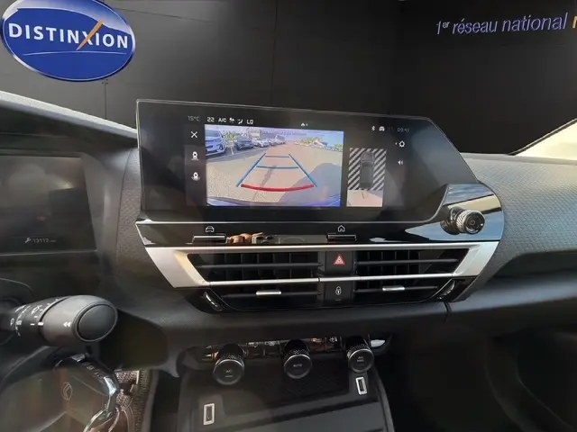 Vue rapprochée du tableau de bord de la Citroën C4 hybride 2025, écran tactile affichant l’aide au stationnement arrière.