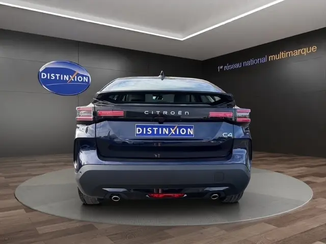 Vue arrière d'une Citroën C4 hybride bleu 2025 avec feux LED et double sortie d'échappement, dans un showroom.