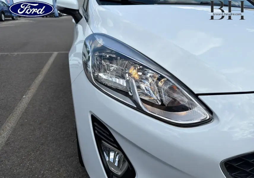 Gros plan sur l'avant droit blanc glacier d'une Ford Fiesta 2020, mettant en valeur le phare et le feu antibrouillard.