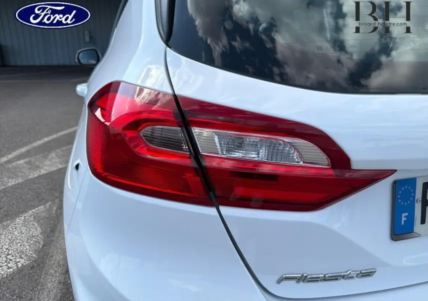 Gros plan sur le feu arrière droit d'une Ford Fiesta blanc glacier, avec le logo Fiesta visible sur le hayon.