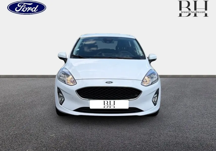 Vue frontale d'une Ford Fiesta blanche Glacier 2020 avec calandre noire et phares allumés sur fond neutre.