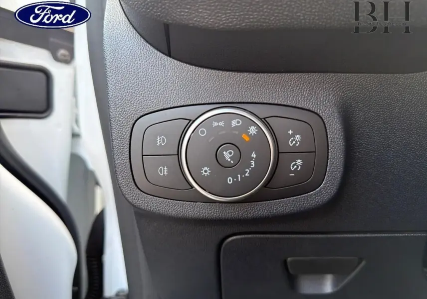 Gros plan sur le bouton de réglage des phares dans l’habitacle d’une Ford Fiesta blanche, côté conducteur.