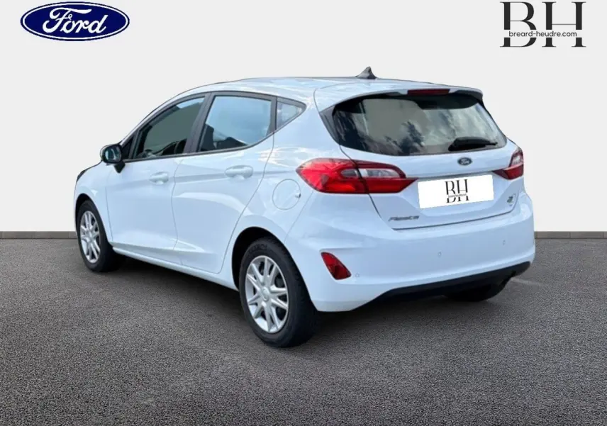 Ford Fiesta blanc glacier vue 3/4 arrière droit, avec feux arrière rouges et jantes argentées.