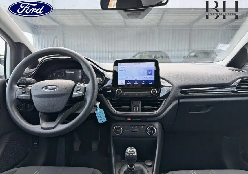 Vue intérieure avant de la Ford Fiesta 2020 avec tableau de bord noir, écran tactile central et levier de vitesses manuel.