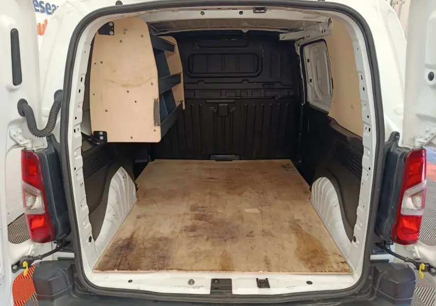 Vue arrière ouverte du Citroën Berlingo blanc montrant l’espace de chargement avec étagères en bois côté gauche.