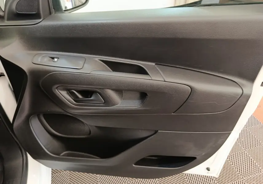 Vue rapprochée de la porte avant gauche noire du Citroën Berlingo blanc, montrant la poignée et les commandes de vitre.