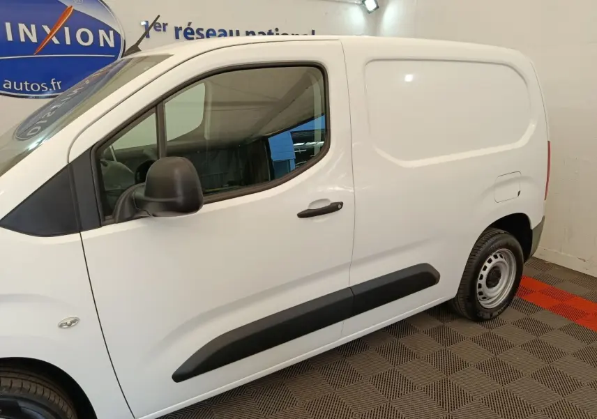 Vue de profil côté gauche d'un utilitaire Citroën Berlingo blanc avec protections latérales noires et jantes acier.