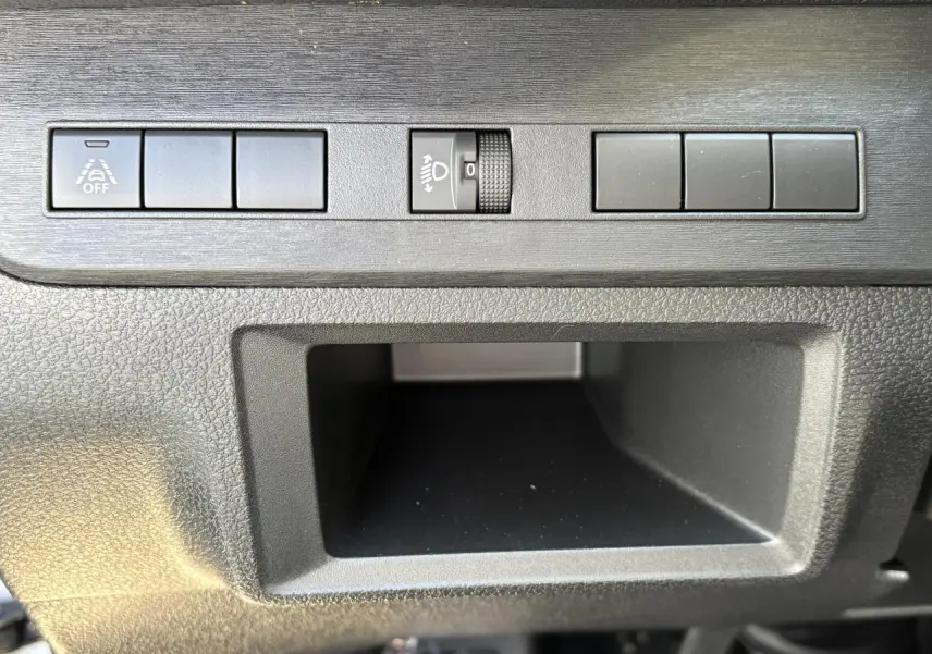 Gros plan sur les commandes de réglage des phares et boutons auxiliaires dans l'habitacle de l'Opel Vivaro blanc.