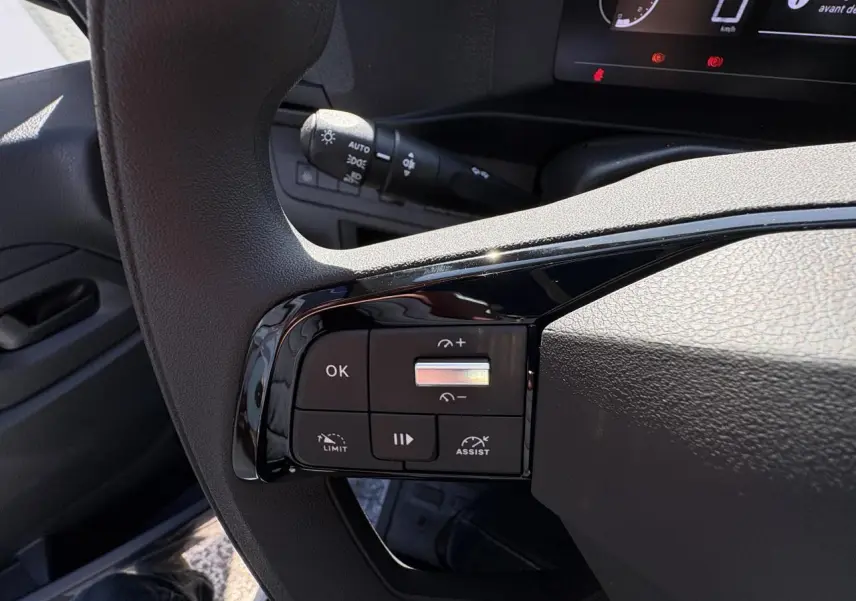 Gros plan sur les commandes au volant à gauche de l'Opel Vivaro 2024, avec boutons de régulateur et assistance.