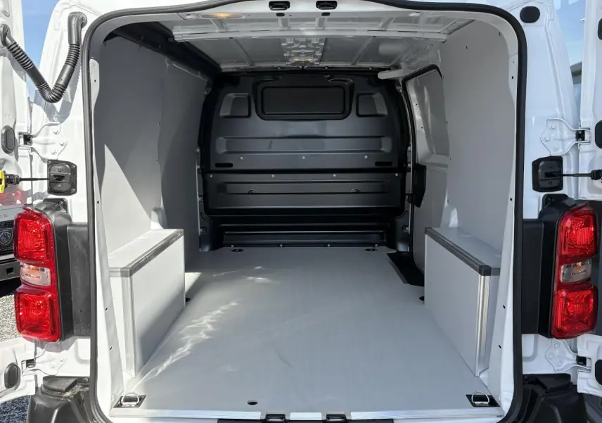 Vue arrière ouverte de l’Opel Vivaro blanc 2024, montrant l’espace de chargement avec plancher et habillages bois.