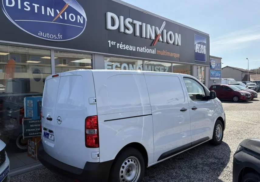 Vue 3/4 arrière droite d’un utilitaire Opel Vivaro blanc stationné devant un concessionnaire.