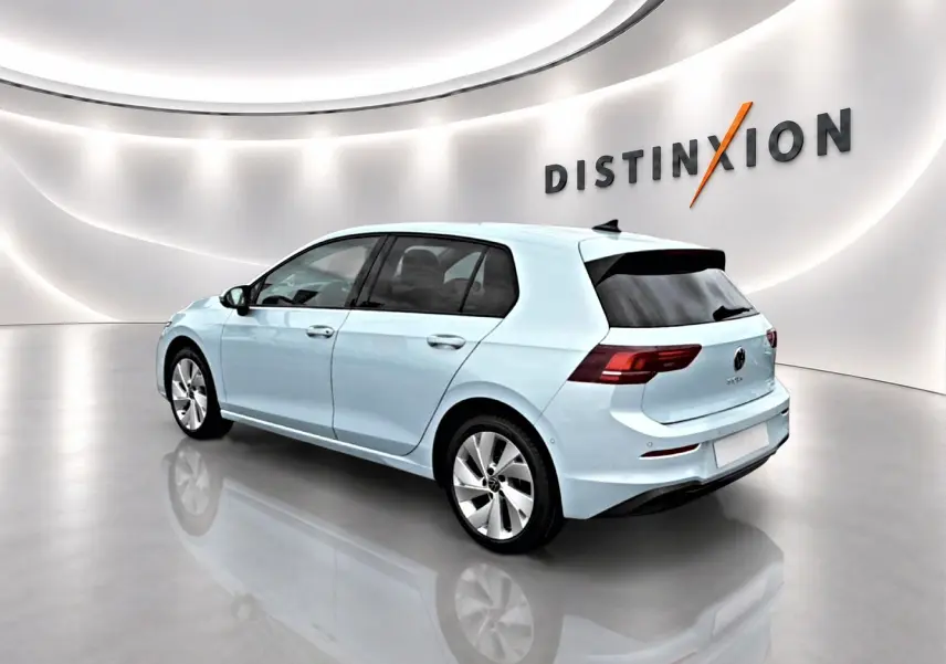 Volkswagen Golf bleu glacier vue 3/4 arrière droit dans un showroom lumineux avec logo Distinxion en arrière-plan.