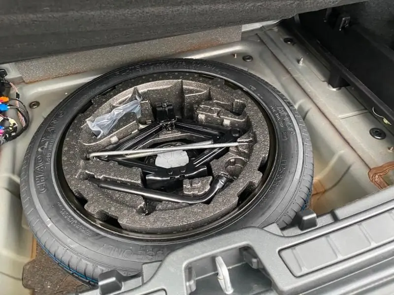 Vue du coffre du Volvo XC40 T3 2020 noir, montrant la roue de secours et les outils de changement de pneu rangés.