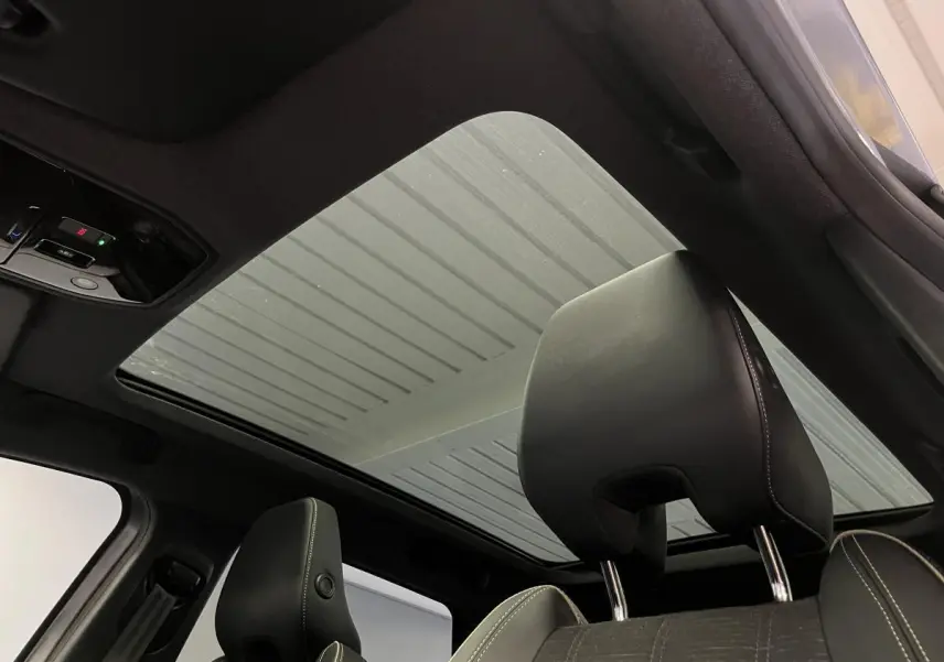 Vue intérieure du toit panoramique fixe et des appuie-têtes noirs avec surpiqûres claires du Renault Austral gris.