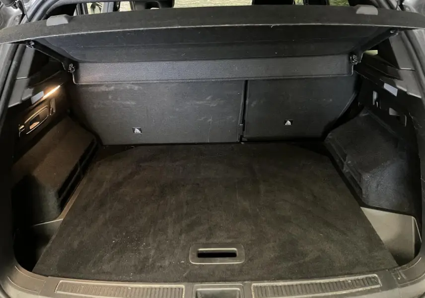 Coffre ouvert vu de l'arrière d'un Renault Austral gris, avec plancher plat et habillage intérieur noir.