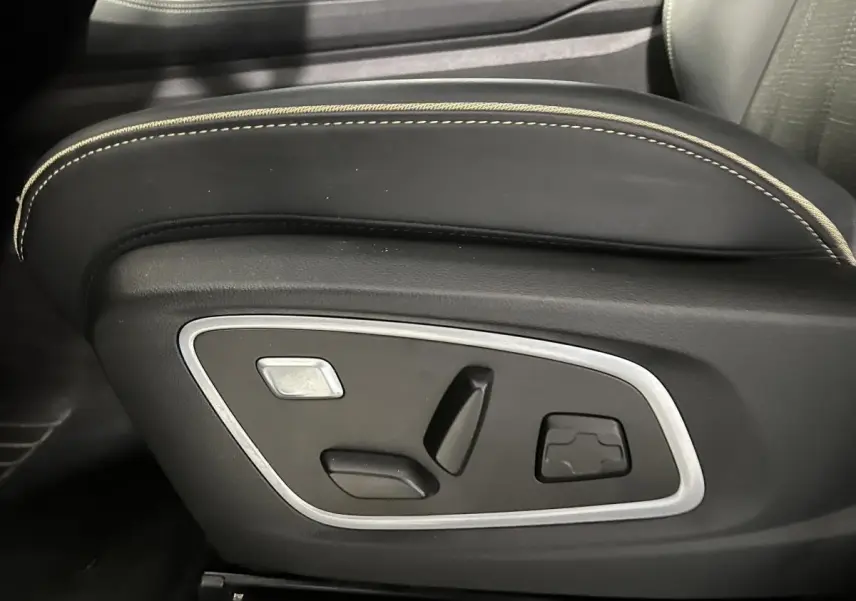 Gros plan sur les commandes électriques du siège conducteur noir avec surpiqûres beiges du Renault Austral 2024.