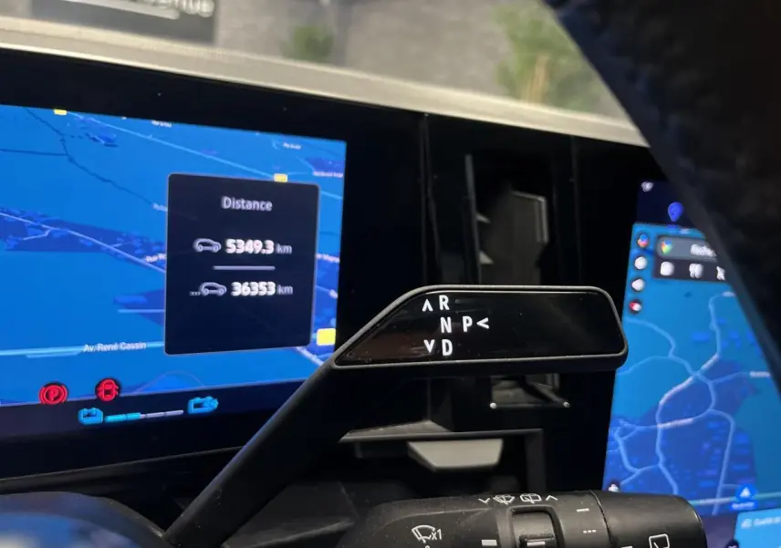 Le levier de boîte automatique noir de la Renault Austral 2024, avec affichage des modes de conduite sur fond d'écran de navigation.