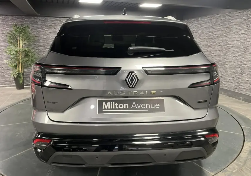 Vue arrière du Renault Austral gris avec feux LED horizontaux et logo central dans un showroom intérieur.