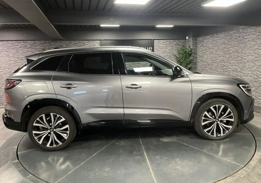 Renault Austral gris schiste vu de profil côté gauche, avec jantes alliage 20 pouces et toit panoramique fixe.