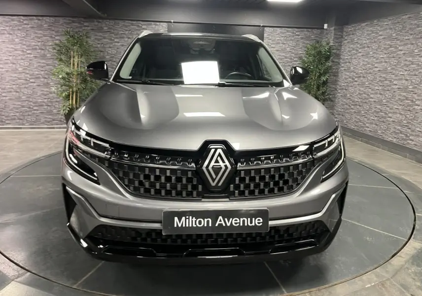 Vue frontale du Renault Austral gris avec calandre damier ice black et logo Renault proéminent, en intérieur showroom.