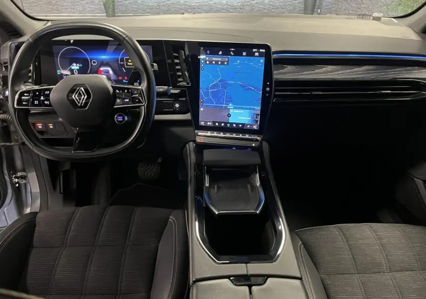 Vue intérieure avant du Renault Austral gris avec tableau de bord numérique et écran tactile vertical central.