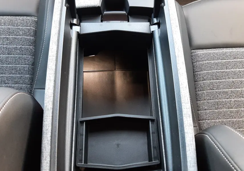 Vue plongeante sur le rangement central ouvert du Peugeot 5008 bleu Ingaro, montrant les sièges et console intérieure.