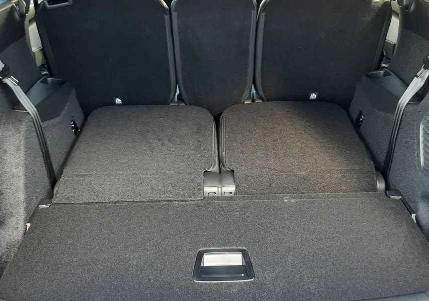 Vue arrière du coffre du Peugeot 5008 bleu Ingaro 2025 avec sièges rabattus et plancher plat visible.